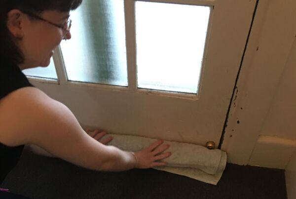 Person placing a rolled towel at the base of a closed door