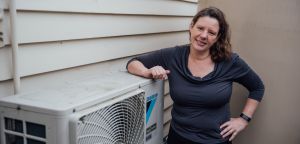 Women outside of house with air-conditioner outlet.