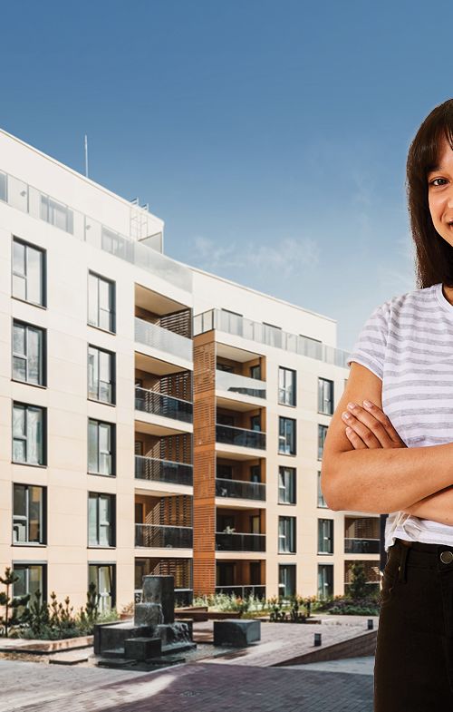 Women standing in front of a photo of am apartment block.