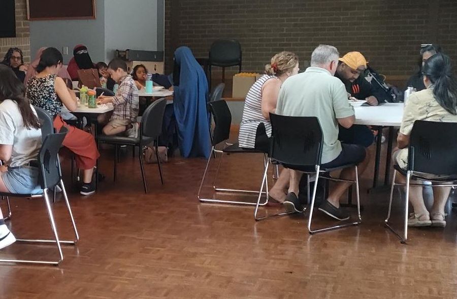 Groups of people sitting around table sin a hall eating lunch