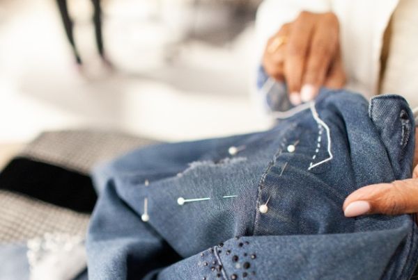 Women sewing to repair a denim jacket.