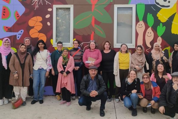 Group of 20 people standing in front of a colourful mural