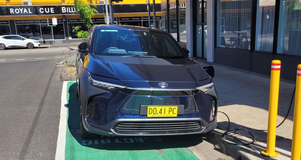 A black car parked in an electric vehicle charging bay in Brunswick.