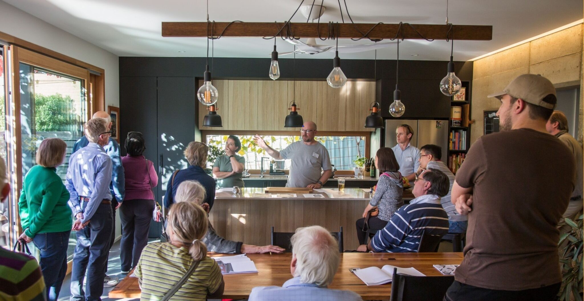 People standing around a kitchen with someone talking and pointing.
