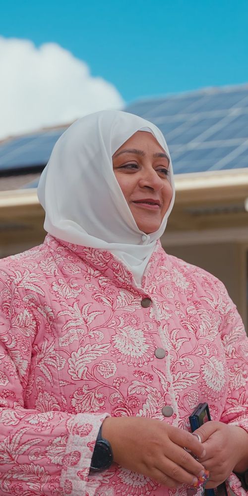 Women standing in front of her home with solar panels in background