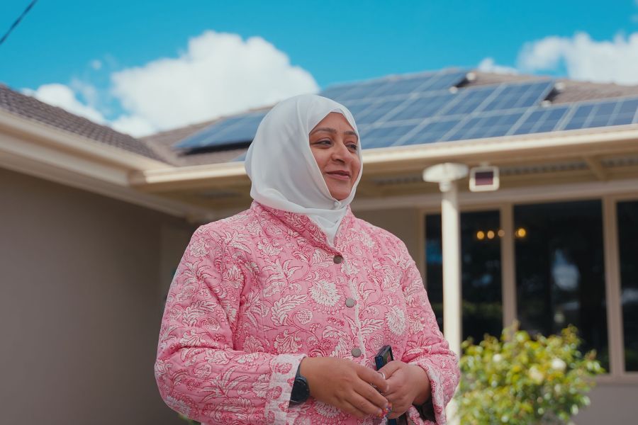 Women standing in front of her home with solar panels in background