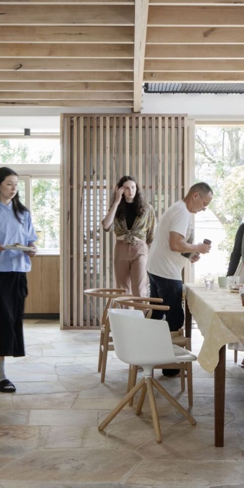 Inside of a light-filled home with family members gathering around a kitchen table