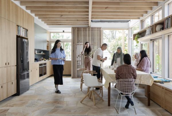Inside of a light-filled home with family members gathering around a kitchen table