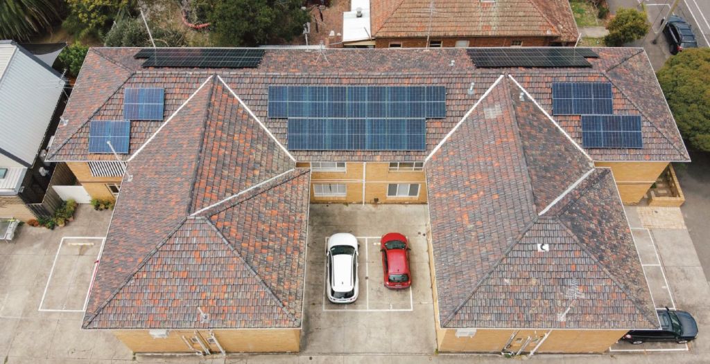 Photo looking down on a block of brick apartments with solar on the roof