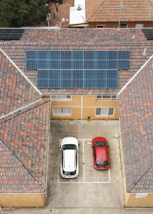 Photo looking down on a block of brick apartments with solar on the roof