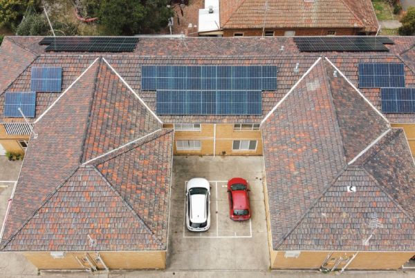 Photo looking down on a block of brick apartments with solar on the roof