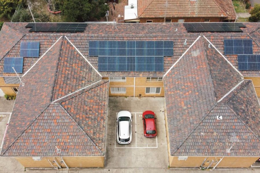Photo looking down on a block of brick apartments with solar on the roof