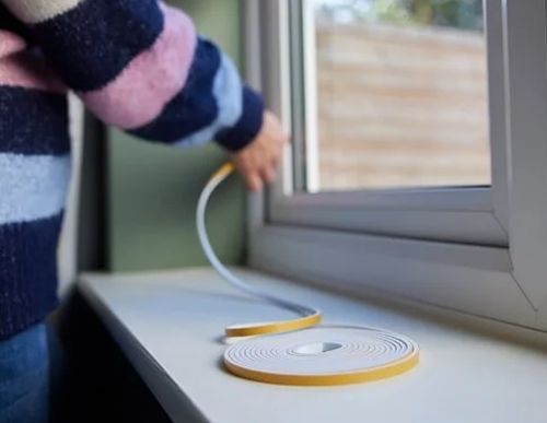 Photo of person placing draught-proofing tape to window frame