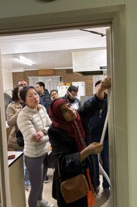 Women putting draughtproofing tape around doorframe with another women watching.