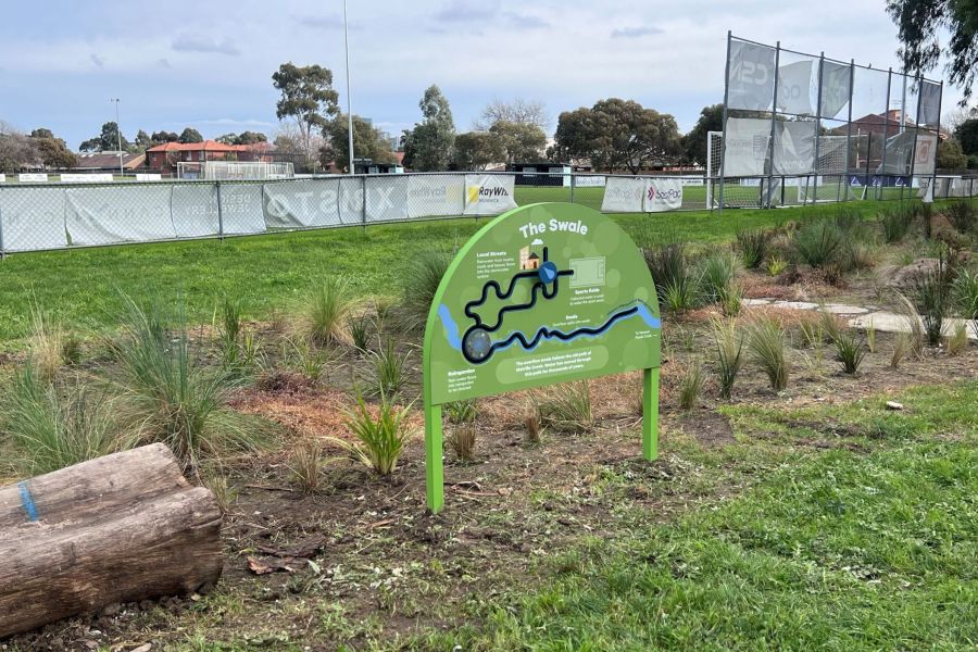 Photo of parkland with lots of plants in front of a football oval. Signage with words The Swale.