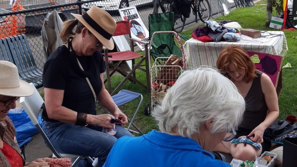 Three women sitting around in a park mending clothes