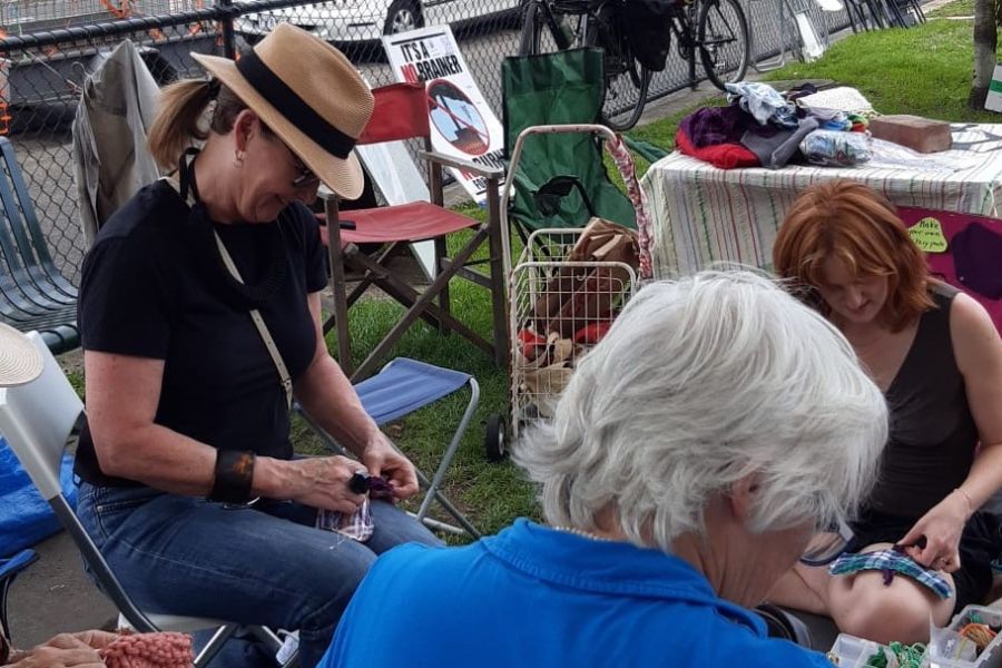 Three women sitting around in a park mending clothes