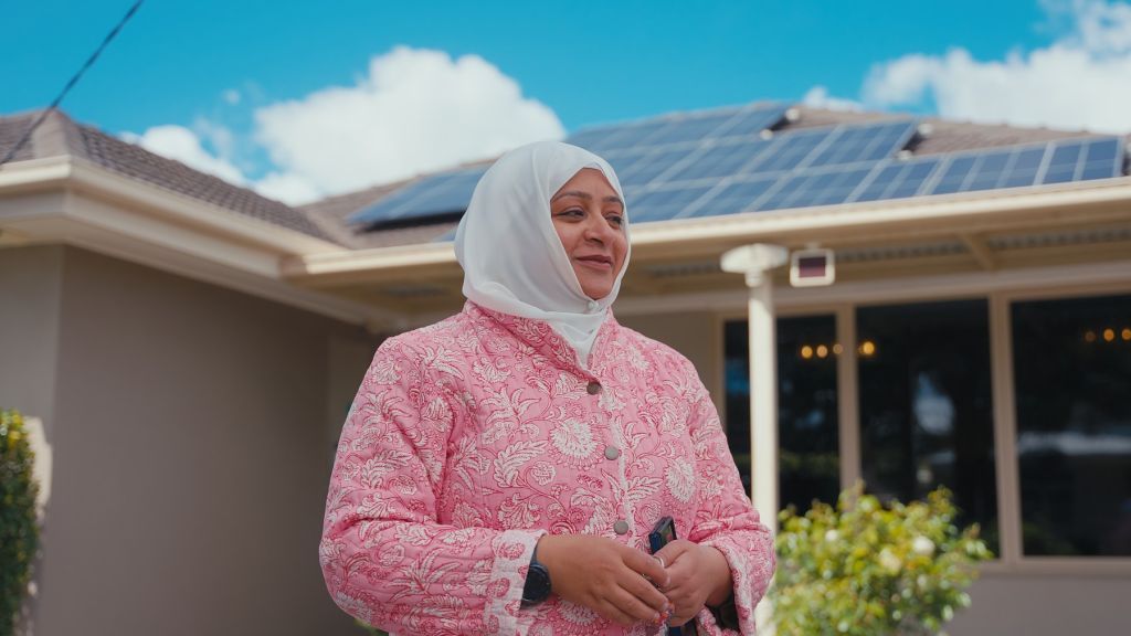 Women standing in front of a house with solar panels on the roof.
