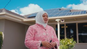 Women standing in front of a house with solar panels on the roof.
