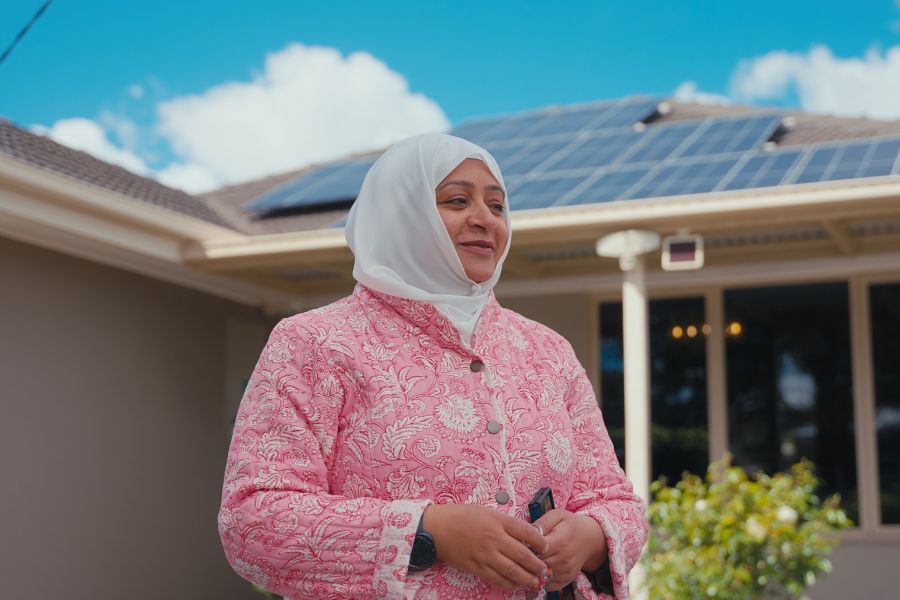 Women standing in front of a house with solar panels on the roof.