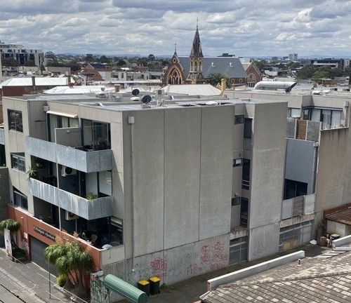 Four level apartment block with surburban skyline in background