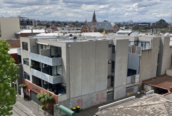 Four level apartment block with surburban skyline in background