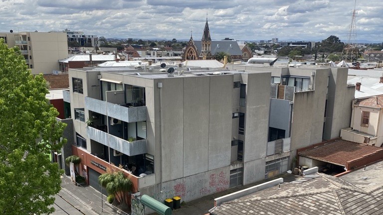 Four level apartment block with surburban skyline in background