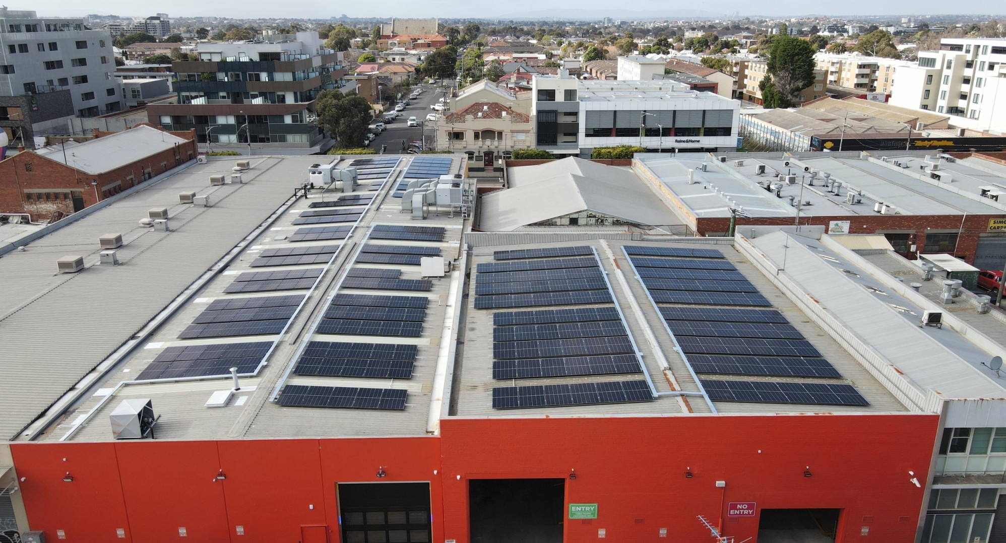 Large rooftop of factory with solar on roof and view of inner city in background