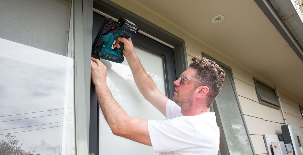 Tradesperson installing draught-proofing around door frame