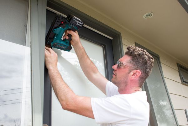 Tradesperson installing draught-proofing around door frame