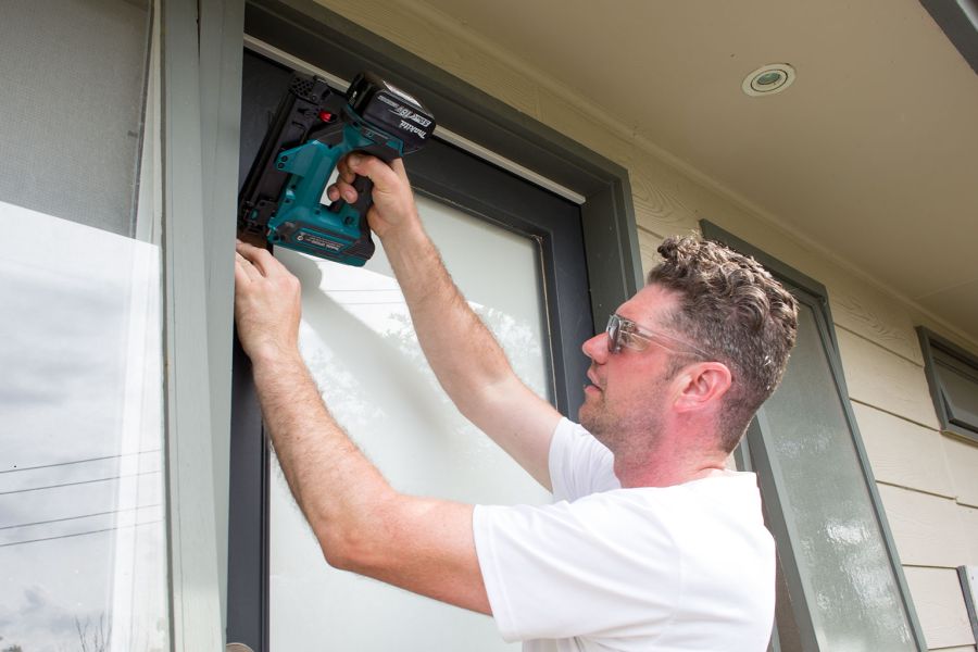 Tradesperson installing draught-proofing around door frame