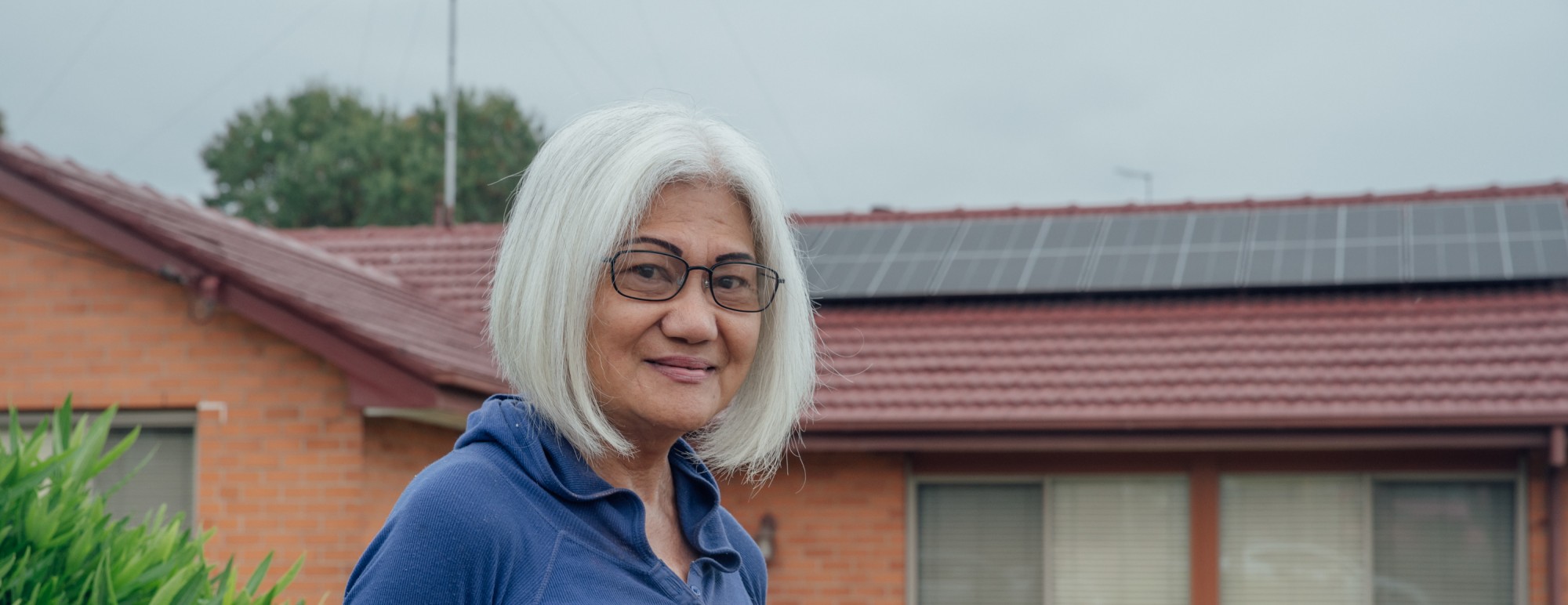 Women standing in front of a red brick house with solar on the roof.
